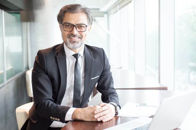 smiling-business-leader-sitting-office-desk